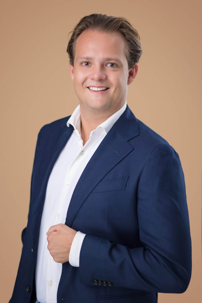 Professionele portretfoto van een makelaar in een blauw pak.