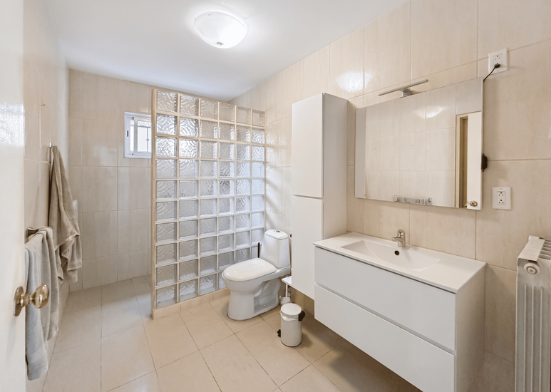 Lichte badkamer met douche, toilet en wastafel, modern design en natuurlijke lichtinval.