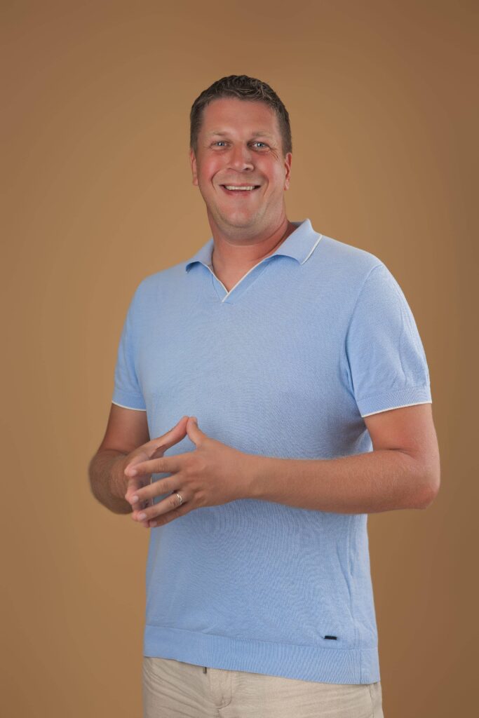 Vriendelijke man in lichtblauwe polo voor Sunset Realtors.