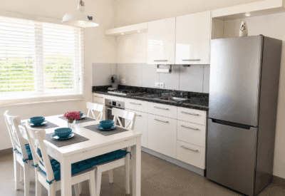 Lichte, moderne keuken met wit meubilair en stainless steel koelkast.