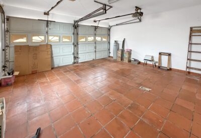 Ruime garage met dubbele garagedeuren en tegelvloer, ideaal voor opslag of auto parkeren.