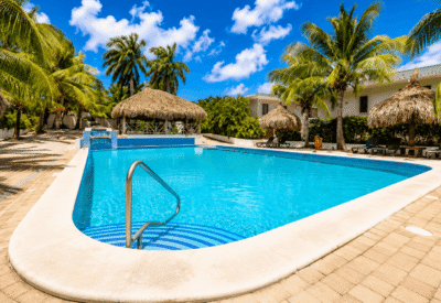 Verfrissend zwembad met palmbomen en strandstoelen op Curaçao.