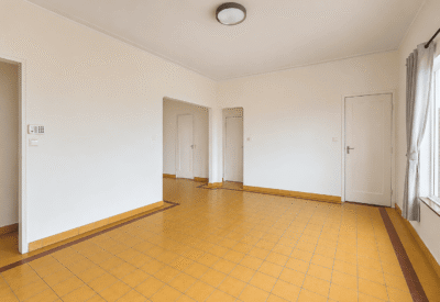 Lichte woonkamer met grote ramen en houten vloer in Biesheuvel.