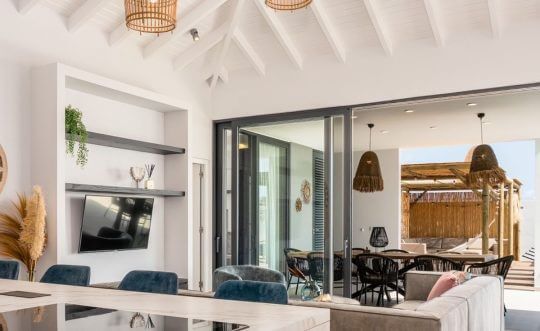 Lichte woonkamer van een woning op Curaçao met openslaande glazen deuren naar het terras.