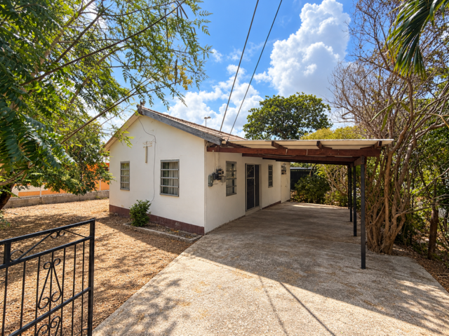 Gezicht op een wit huis met carport en tuin in Willemstad, Curaçao.